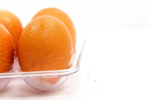 Eggs in plastic box on the white background. Droplets of water on eggs. Stock Photos