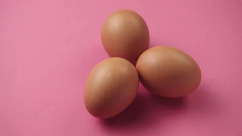 Eggs rotate on pink background. Three fresh, organic and healthy chicken egg. Stockbeeldmateriaal 181171796