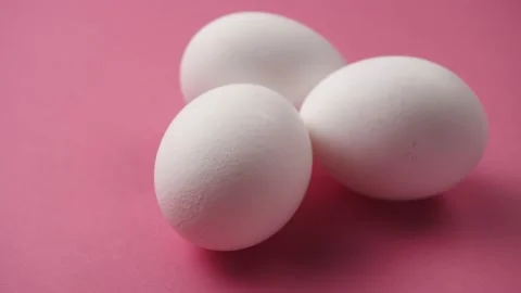 Eggs rotate on pink background. Three fresh, organic and healthy chicken egg. Stockbeeldmateriaal 181172941