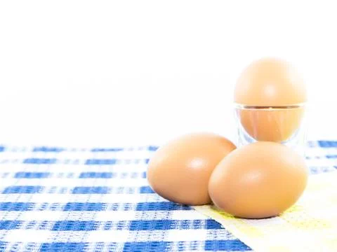 Eggs set on table mat and shot glass Stock Photos