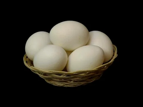 Eggs in a small basket on a black background. Stock Photos
