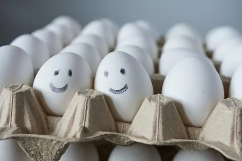 Eggs with smiley faces in carton box, closeup Stock Photos