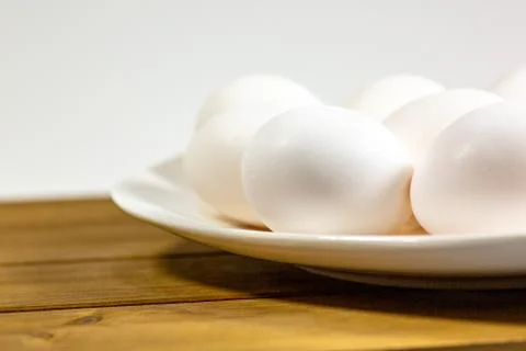 Eggs on a while plate sitting on the kitchen table waiting to be cracked Stock Photos