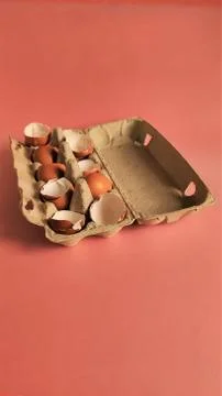 Eggshell halves in recycled cardboard packaging on a pink background. Broken Stock Photos