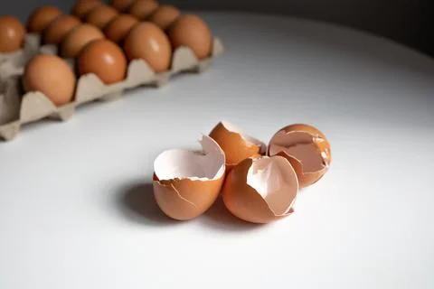 Eggshells and eggs in a paper tray on white table Stock Photos