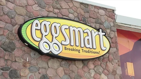 Eggsmart breaking traditions restaurant store sign logo yellow green white Stock Footage 250282483