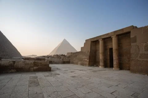 Egyptian temple with pyramid behind at dawn Stock Photos