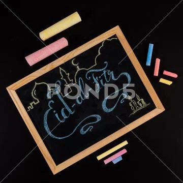 Eid al Fitr greeting hand written with colorful chalk on blackboard - top vie Stock Photos