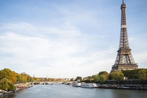 The Eifel tower surrounded by the river greenery and a bridge under a cloudy  Stock Photos