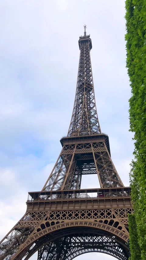 Eiffel Tower and lush tree crowns against the sky in spring in Paris, France.  Stock Footage 311942468