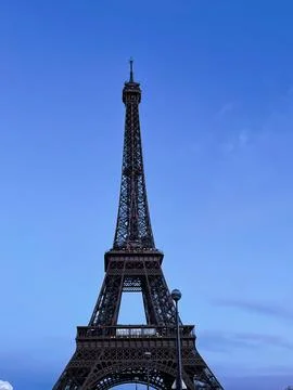 Eiffel Tower captured at dusk with a clear Parisian blue sky backdrop Stock Photos