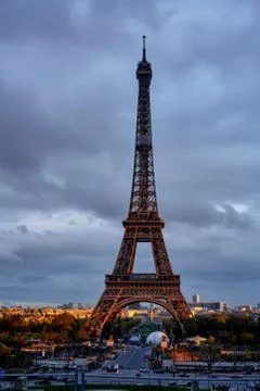 Eiffel Tower in cloudy weather in the rays of the setting sun Stock Photos