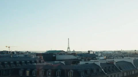 Eiffel tower emerging from parisian rooftops under clear sky Video stock 310874754