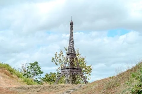 The Eiffel Tower is a large, old structure that is surrounded by trees and grass Stock Photos