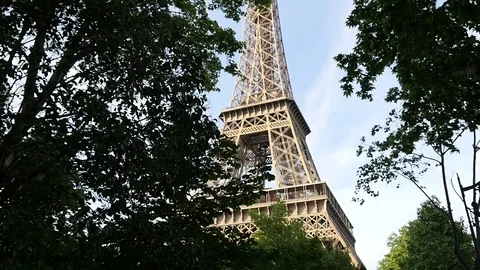 The Eiffel Tower in Paris through a trees crowns in evening time slow motion Stock Footage 76692252
