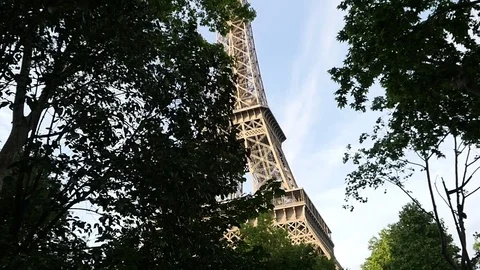 The Eiffel Tower in Paris through a trees crowns in evening time slow motion  Stock Footage 76692258