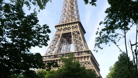 The Eiffel Tower in Paris through a trees crowns in evening time Stock Footage 76839404
