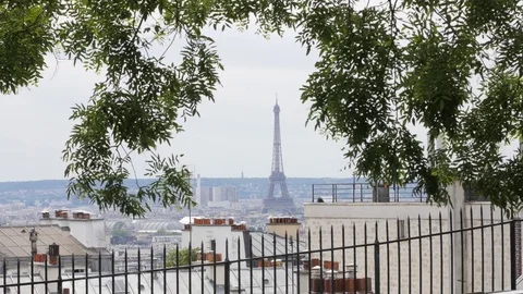 The Eiffel Tower in Paris view through trees green crowns and building roofs  Stock-Footage 76794676