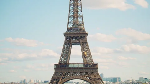 The Eiffel Tower rises above Paris on a clear day, with the cityscape and clouds Vídeo Stock 313412289