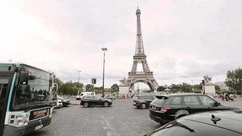 The Eiffel Tower with traffic. Blue cloudy sky in summer day with green trees Stock Footage 128859311