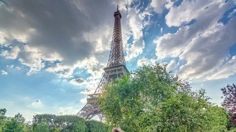 The Eiffel tower with warm rays of light in clouds during sunset timelapse .. Stock Photos