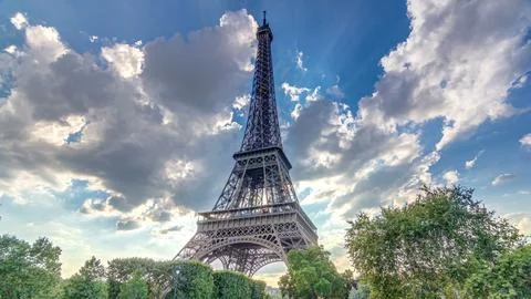 The Eiffel tower with warm rays of light in clouds during sunset timelapse .. 写真素材