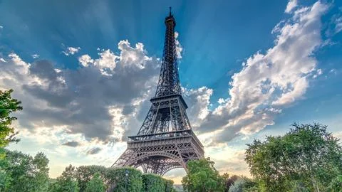 The Eiffel tower with warm rays of light in clouds during sunset timelapse .. Stock Photos