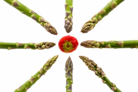 Eight asparagus spears pointing at one strawberry Stock Photos