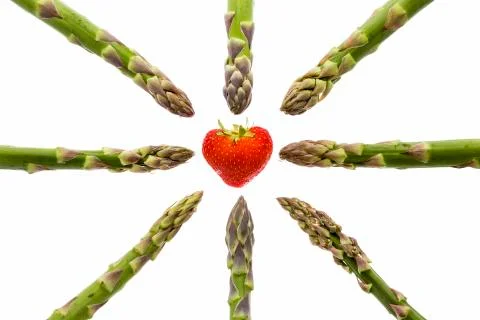 Eight asparagus tips pointing at one strawberry Stock Photos