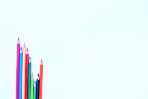 Eight different colored pencil crayons gathered in a wave saved row on a whit Stock Photos