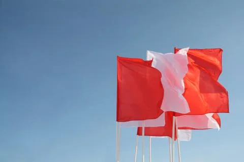 Eight red and white flags flutter in wind at background of blue pure sky Stock Photos