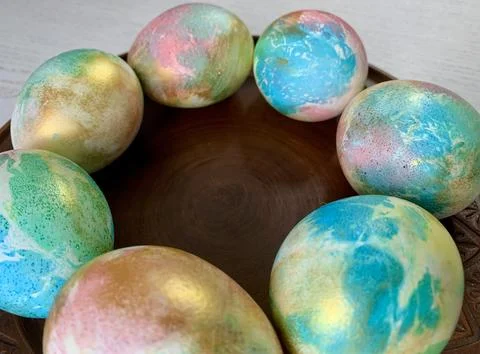 Eight vibrant, hand-painted Easter eggs in shades of blue, green, gold, and pink Stock Photos