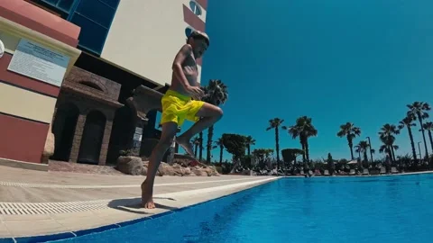 Eight-year-old boy jumping into the pool. He is having fun on a sunny summer day Stock Footage 196835815