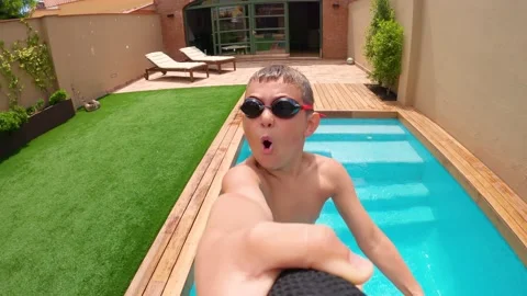 Eight-year-old boy records himself as he jumps into the pool. Stock Footage 137520317