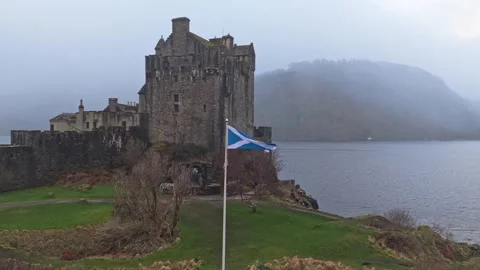 Eilean donan castle with a waving scottish flag on a foggy day Video stock 334058271