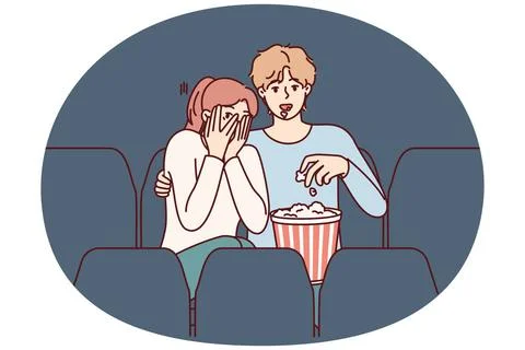 Ein Mann und ein Mädchen sehen sich einen Horrorfilm im Kino an und essen .. Stock Photos
