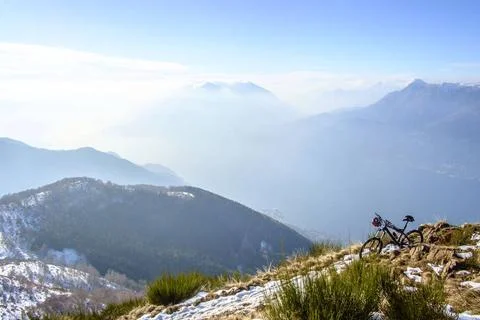 Ein Mountainbike steht in den Bergen am Comersee auf einem verschneiten Wa... Stock Photos