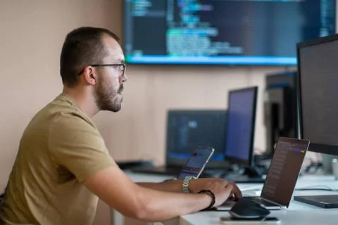 Ein Programmierer testet fleißig Smartphone-Anwendungen, während er in sei. Foto stock