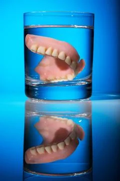 Ein Zahnersatz wird in einem Glas mit Wasser gereinigt. Richtige Hygiene. ... 스톡 사진