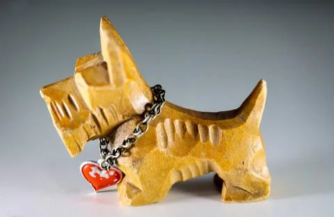 Eine geschnitzte Figur eines Hundes mit einer Kette um den Hals. Eine gesc... Stock Photos