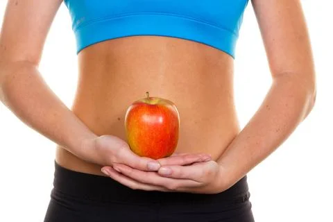 Eine junge Frau in Sportbekleidung hält einen Apfel in der Hand McPBBO ***.. Stock Photos