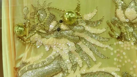 An elaborate gold and white sequin and bead embroidered dragon motif  Stock Footage 340628648