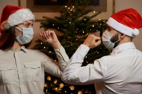 Elbow greeting to avoid the spread of COVID against background of Christmas t Stock Photos