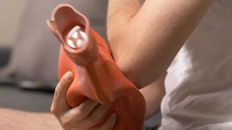 Elbow Injury Closeup Using a Hot Water Bag To Relief The Pain Stock Footage 92643869