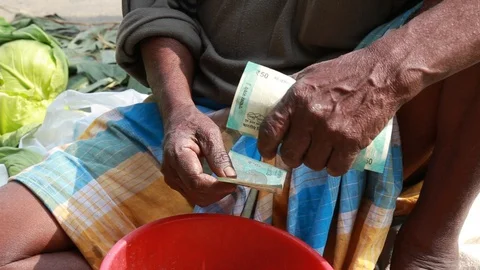 An Elder Counts His Rupees along a Busy Street Stock Footage 129107977