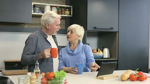 Elder couple at the kitchen. Drinking tea (or coffee) and talking. Stock Footage 102327234