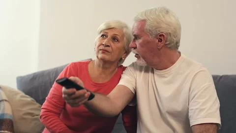 Elder couple sitting on the sofa, watching tv and discussing news. Stock Footage 102569327