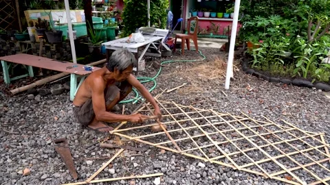 Elder Indonesian worker constructing wooden fence frame, city of Solo Video stock 165580973