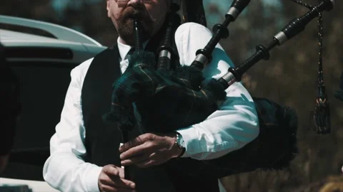 Elder man with beard playing scottish bagpipe outside in nature Stock Footage 151998637