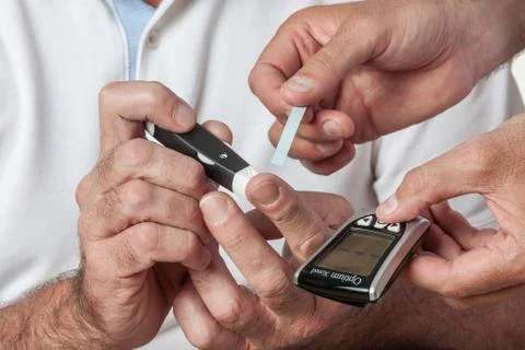 Elder man using the Glucose meter Фото